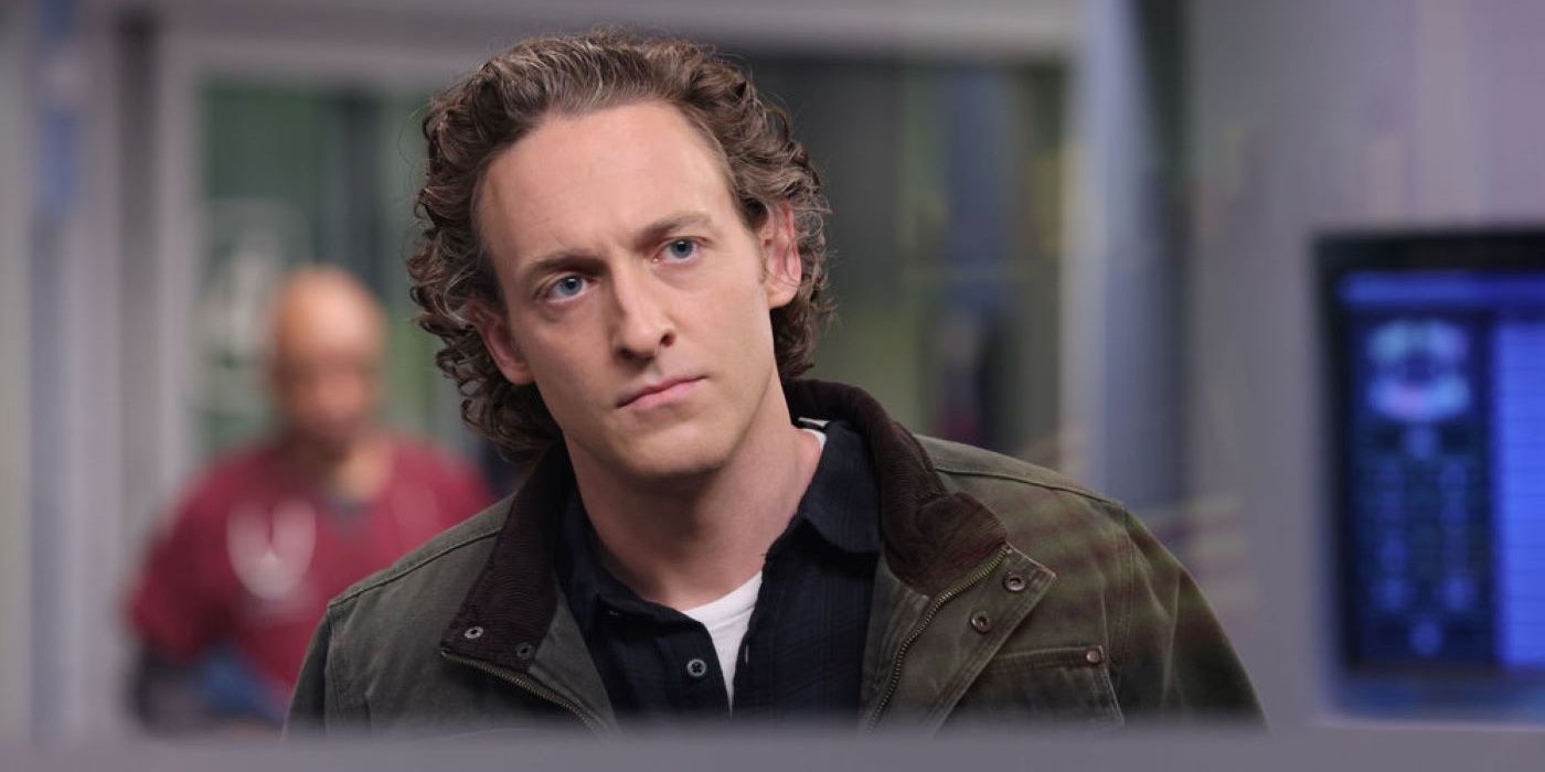 Sean Archer usa una chaqueta a cuadros verde oscuro y marrón sobre una camisa azul oscuro en el episodio 20 de la temporada 8 de Chicago Med.