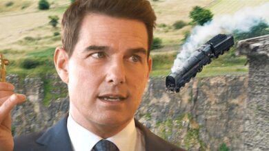 Tom Cruise in Mission Impossible 7 smugly holding up a key backdropped by a train plunging off the end of a collapsed bridge into a ravine