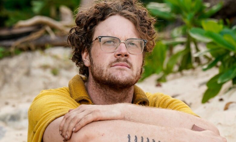 Kane Fritzler Survivor 44 gazing in distance in yellow shirt on beach