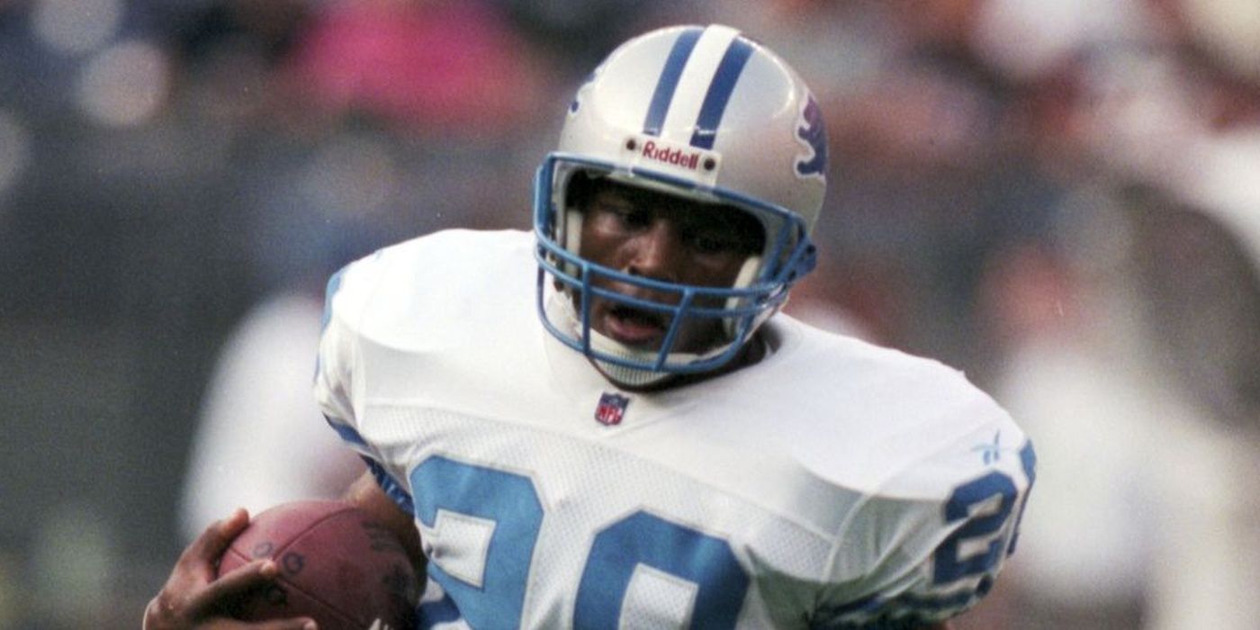 Barry Sanders de los Detroit Lions sosteniendo una pelota de fútbol con uniforme blanco