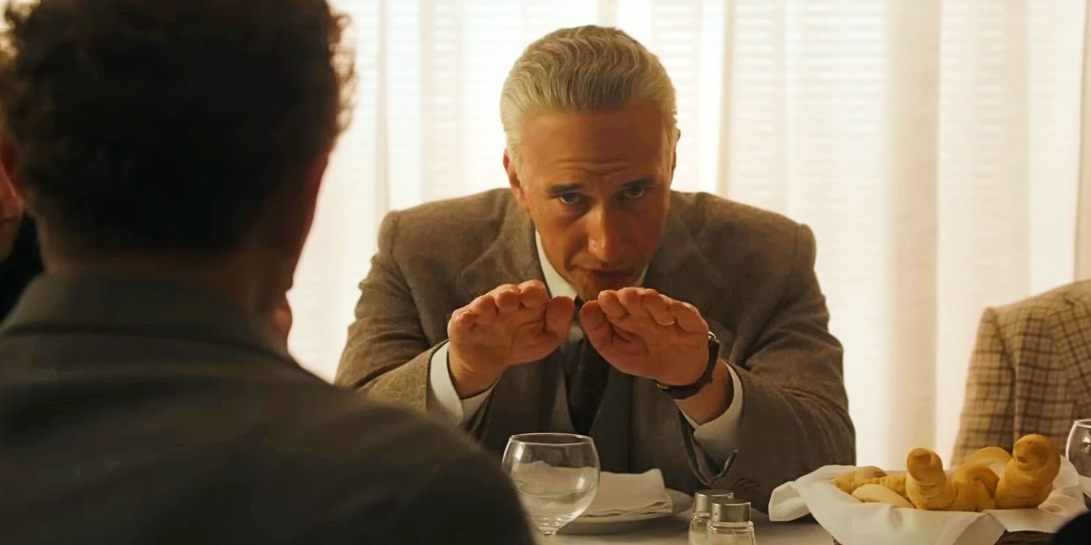 Adam Driver como Enzo Ferrari haciendo un gesto paralelo con las manos.