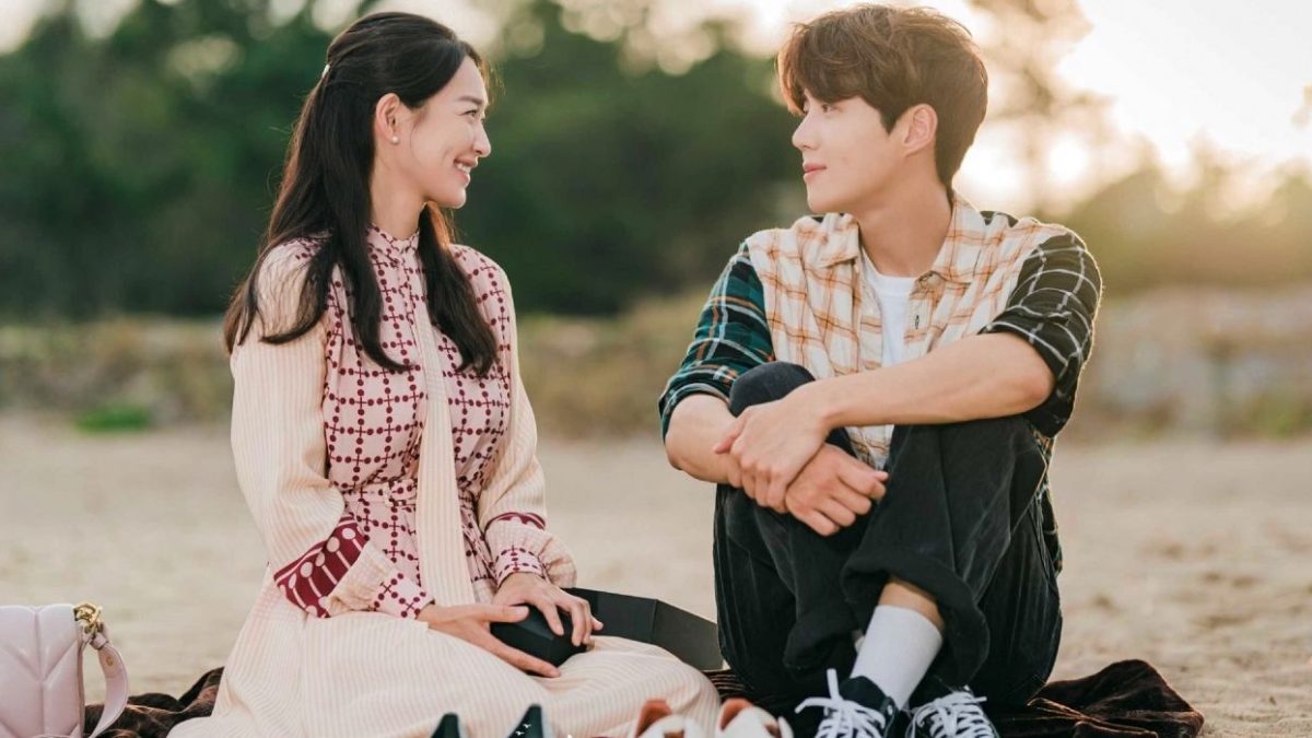 Two characters sitting on a beach and smiling at one another in Hometown Cha-Cha-Cha