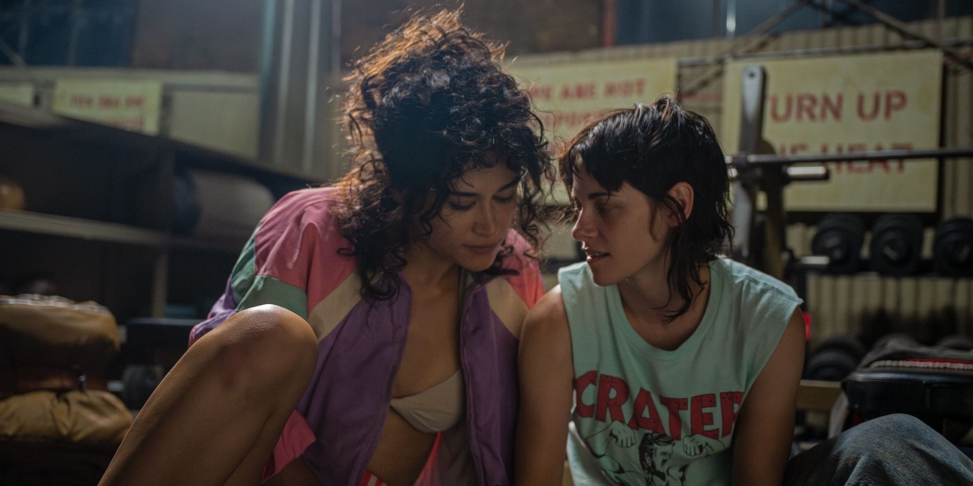 Katy O'Brian y Kristen Stewart se inclinan la una hacia la otra en el gimnasio en Love Lies Bleeding