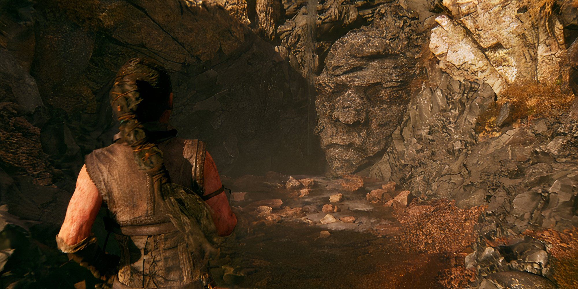 Senua se acerca a una cara oculta tallada en las rocas en Hellblade 2