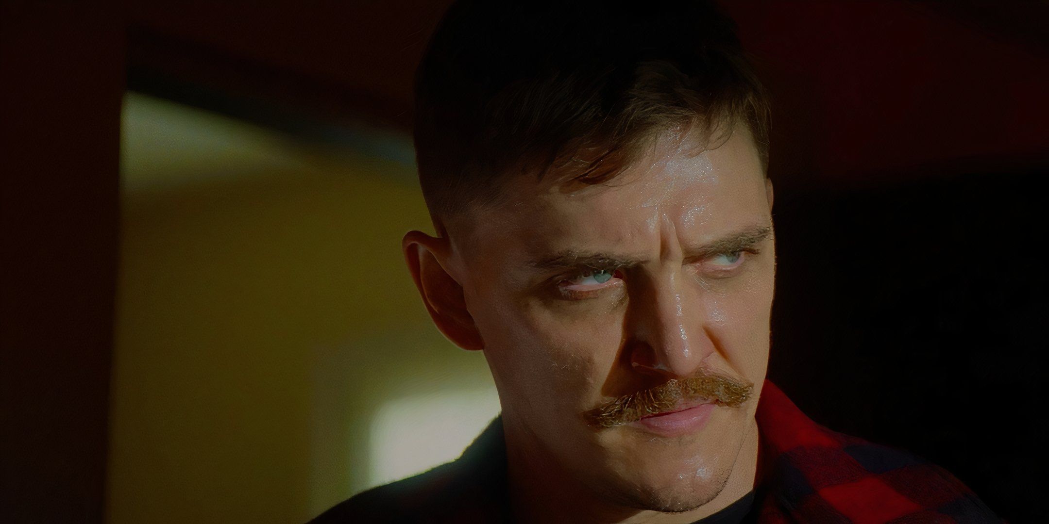 Kyle Gallner como el Demonio que mira enojado algo en una habitación oscura en Strange Darling