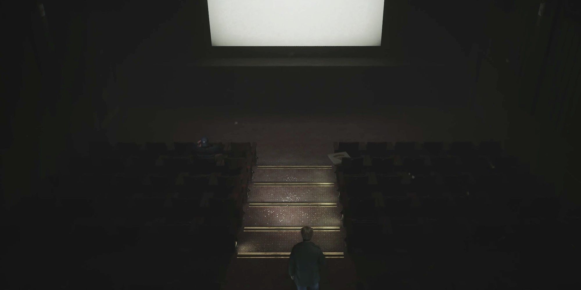 Silent Hill 2 Remake Theatre: vista desde arriba de una pantalla de cine en blanco y asientos mientras James se acerca a Eddie