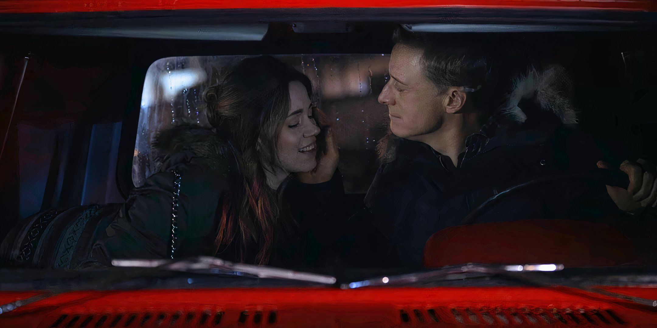 Harry con la mano en la mejilla de D'Arcy, sentado dentro de un camión rojo