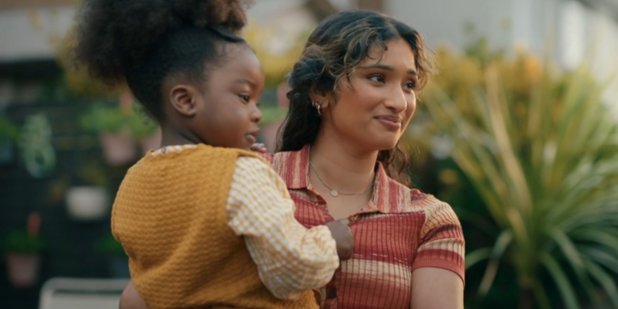 Varada Sethu como Belinda Chandra sosteniendo a Poppy en su jardín mientras se despiden del Doctor en el episodio de la temporada 15 de Doctor Who "The Reality War".