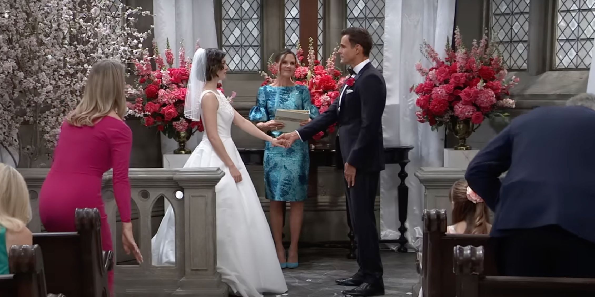 Hospital General Drew y Willow de pie en el altar con damas de honor detrás de ellos y miembros de la audiencia sentados