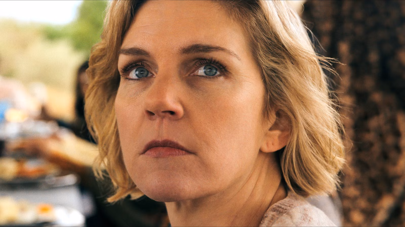 Carol de Rhea Seehorn mirando seriamente por encima del hombro en Pluribus