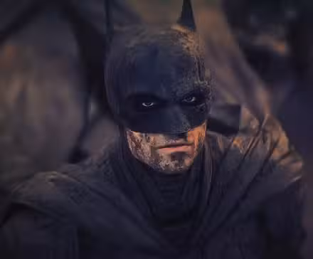 Batman de Robert Pattinson con suciedad en toda la cara y traje mirando hacia arriba en The Batman