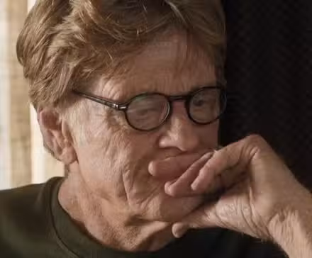 Robert Redford como Bill Bryson en Un paseo por el bosque mirando la computadora