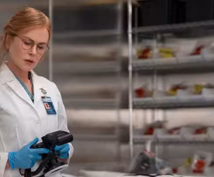Nicole Kidman como Kay Scarpetta mirando una mesa de examen en un laboratorio en Scarpetta.