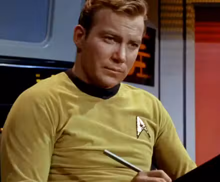 William Shatner como el Capitán Kirk escribiendo en su libreta en Star Trek: La serie original.