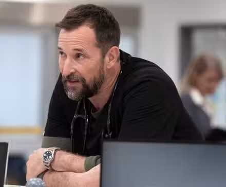 Robby inclinado sobre un escritorio hablando en la temporada 2 de The Pitt