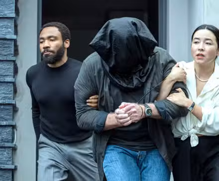 Donald Glover y Maya Erskine con un hombre encapuchado en Mr. & Mrs. Smith