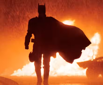 Batman de Robert Pattinson camina frente al fuego bajo la lluvia en The Batman de Matt Reeves
