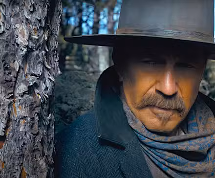 Kevin Costner mira desde detrás de un árbol en una escena de Horizon: An American Saga