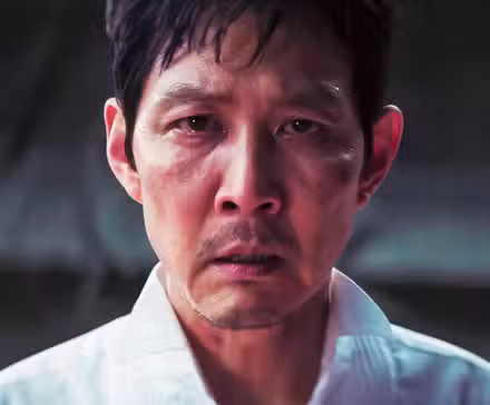 Lee Jung-jae como Gi-hun mirando a la cámara con ojos llorosos en el final de la temporada 3 de Squid Game