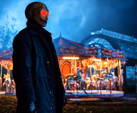 El asesino de Heart Eyes acecha a una víctima frente a un carrusel en Heart Eyes
