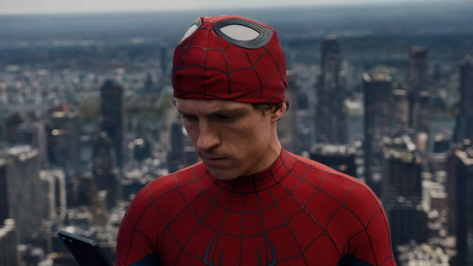 Spider-Man de Tom Holland con la máscara puesta y mirando su teléfono en Spider-Man: Brand New Day
