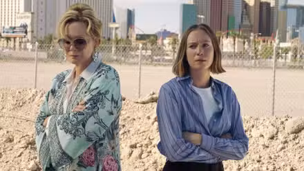 Jean Smart y Hannah Einbinder en la playa, de pie con los brazos cruzados en una escena de Hacks