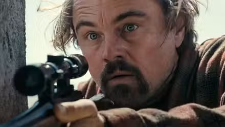 Bob en primer plano luciendo sorprendido mientras sostiene su rifle en Una batalla tras otra
