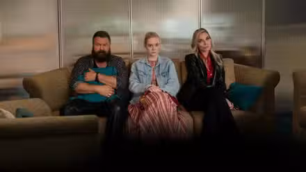 Nick Offerman, Ell Fanning y Michelle Pfeiffer sentados en un sofá luciendo sombríos