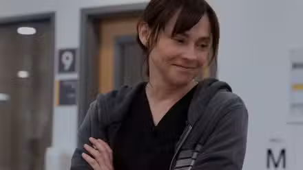 Fiona Dourif como la Dra. Cassie McKay sonriendo con los brazos cruzados en The Pitt.