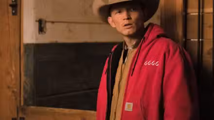 Jimmy (Jefferson White) de pie en un establo en el rancho 6666 de Yellowstone