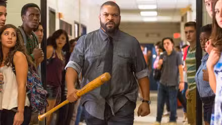 Ice Cube caminando por un pasillo sosteniendo un murciélago mientras los niños observan.