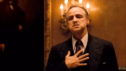 Marlon Brando como Don Corleone tocándose el pecho en El Padrino