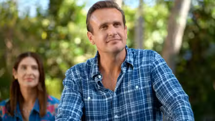 Jason Segel como Jimmy sonríe levemente mientras Cobie Smulders como Sofi está detrás de él en Shrinking.
