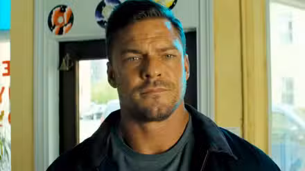 Alan Ritchson mirando a alguien en la temporada 3 de Reacher