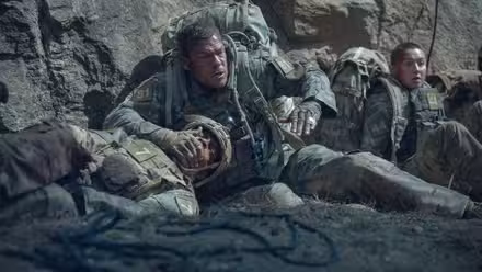 Alan Ritchson cubre la boca de un compañero soldado mientras se esconde en War Machine