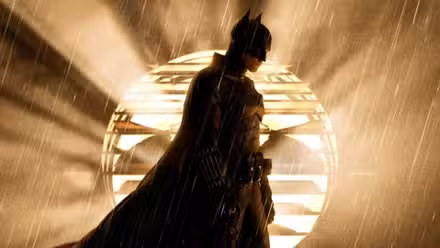 Robert Pattinson como Batman parado frente a la batiseñal en The Batman