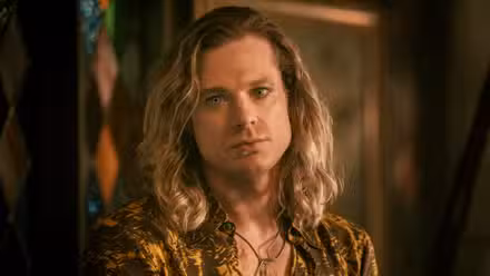 Sam Reid como Lestat, mirando hacia un lado, en una imagen fija de The Vampire Lestat