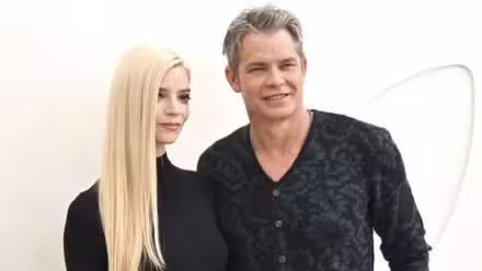 Anya Taylor-Joy y Timothy Olyphant sonríen levemente mientras caminan juntos por la alfombra roja en un evento.