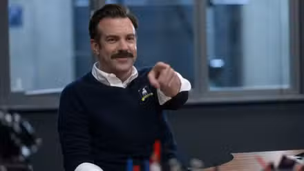 Ted señalando con el dedo y sonriendo en Ted Lasso