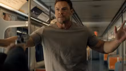 Alan Ritchson como Reacher detenido a punta de pistola.