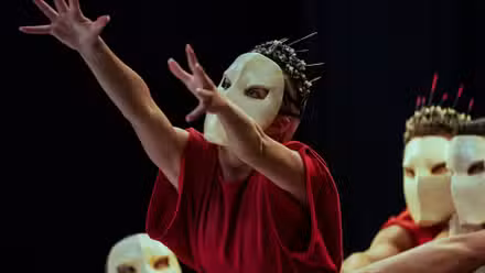 Imagen fija del episodio 2 de Archive 81 en Netflix, un actor con una máscara en la cara y una túnica roja levanta la mano en el aire.