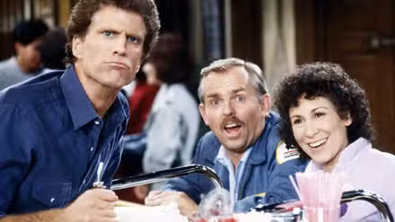 Carla sonriendo y Sam frunciendo el ceño a la cámara.