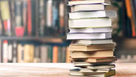 Pila de libros frente a una estantería