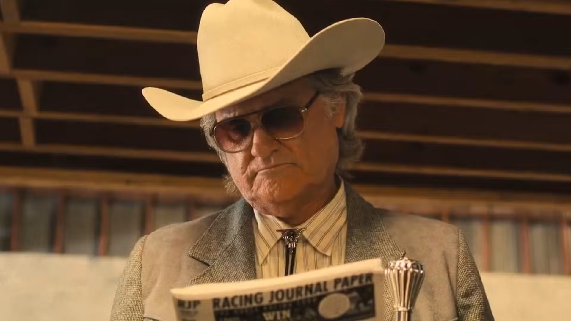 Kurt Russell mirando el periódico en Rivales de Amziah King