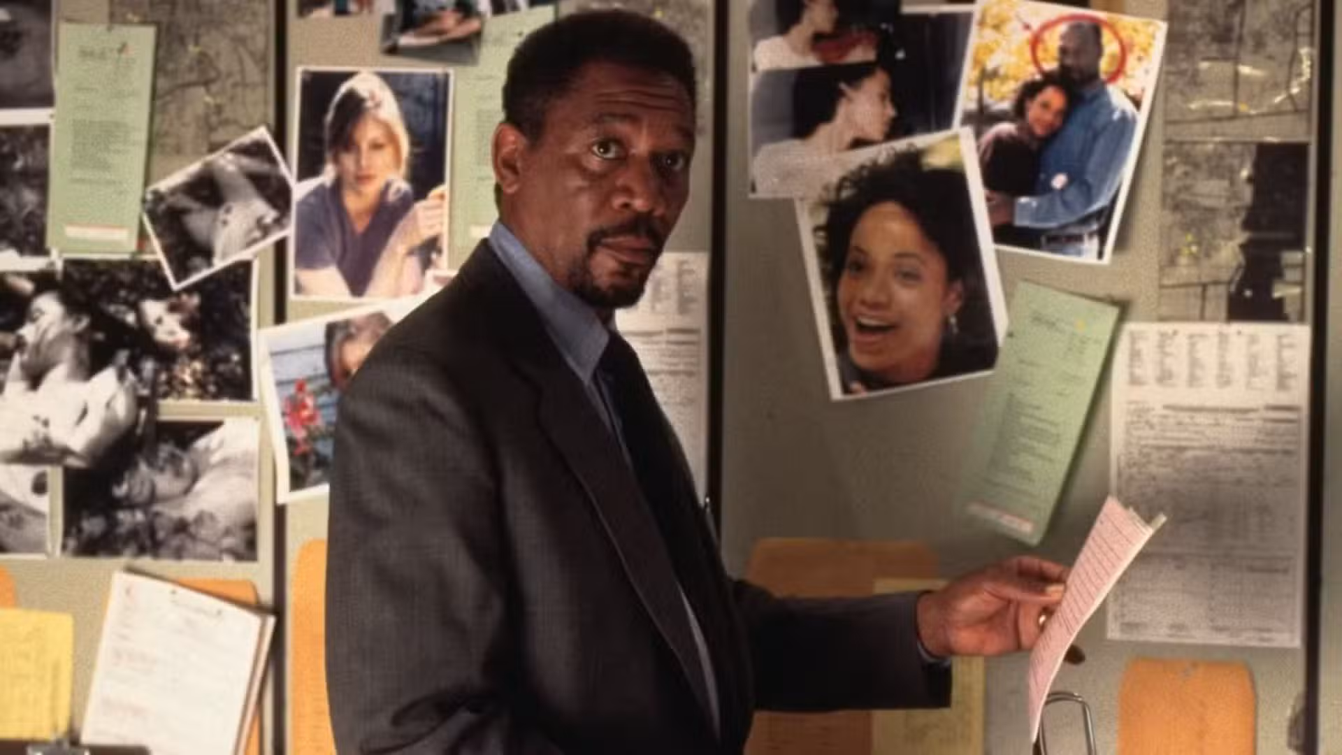 Morgan Freeman como Alex Cross mirando fotos en Kiss the Girls