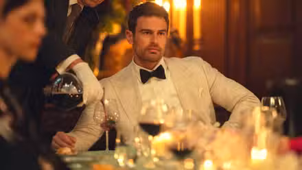 Eddie de Theo James parece enojado mientras alguien le sirve vino en la temporada 2 de The Gentlemen