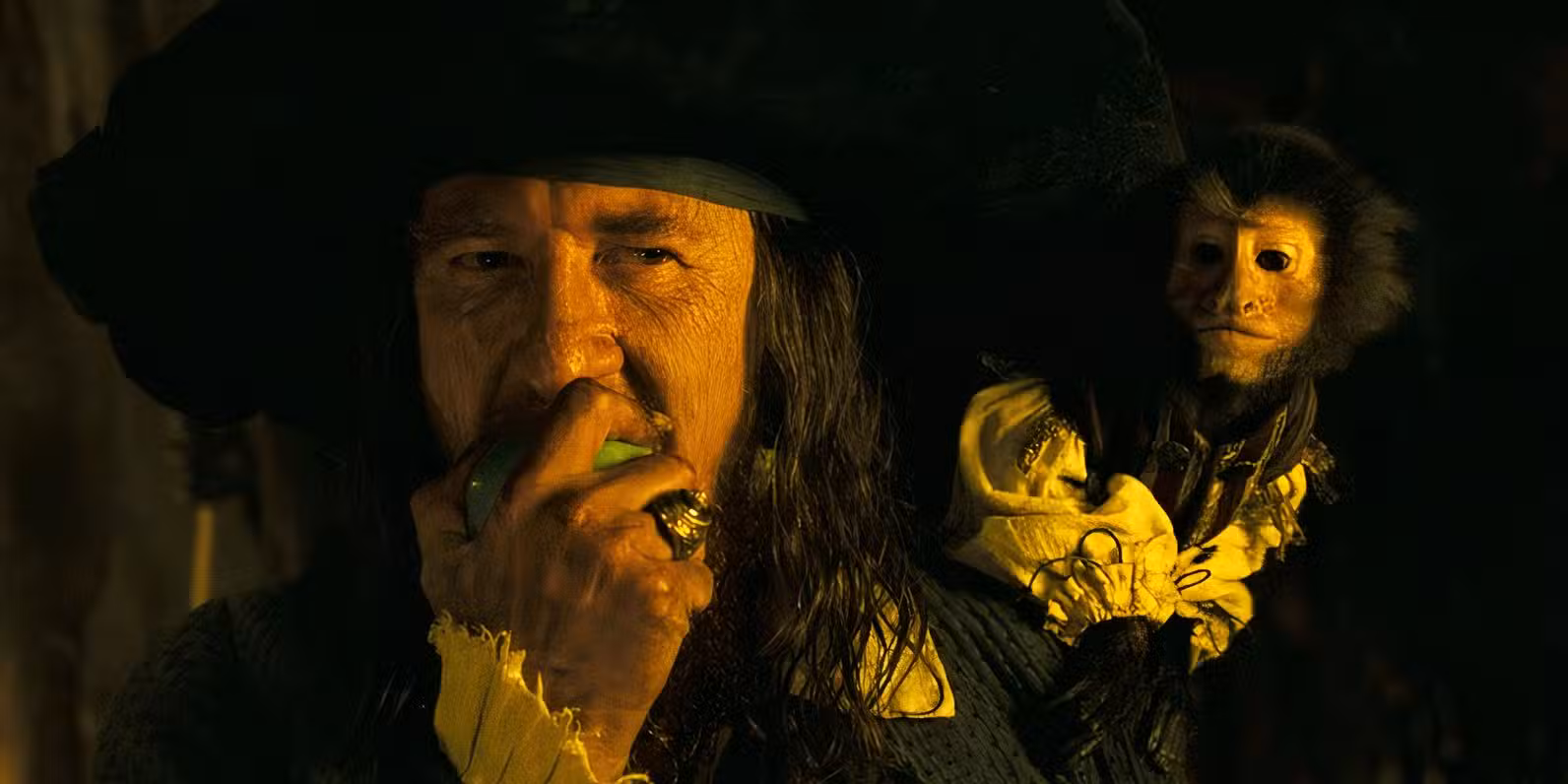 El Capitán Barbossa (Geoffrey Rush) mordiendo una manzana con el mono en el hombro al final de Piratas del Caribe: El cofre del hombre muerto