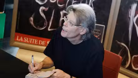 Stephen King charla con un fan mientras firma su libro en un evento