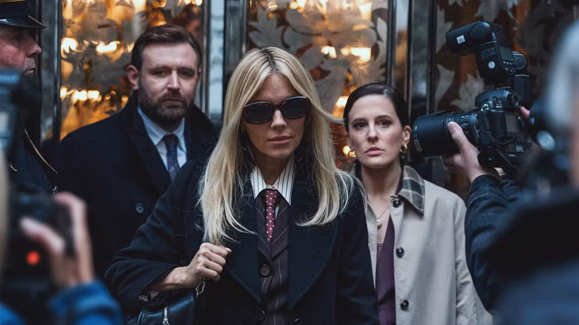 Carla camina entre fotógrafos con sus abogados detrás de ella en War de HBO