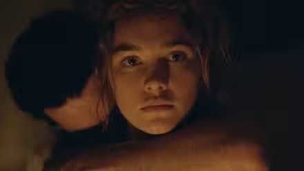 Florence Pugh mira fijamente a la cámara con un brazo alrededor del cuello en East of Eden
